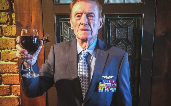 Old sailor in grey tux, holding up a glass of wine