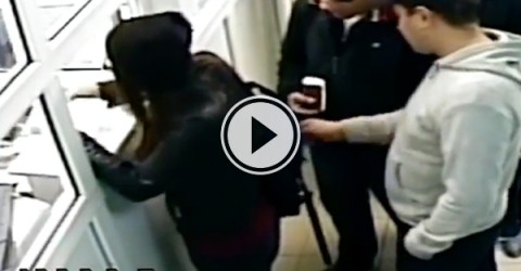 Guy in grey hoodie messes with the backpack of a person in front of him at the counter