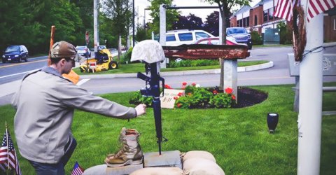 Young guy paying his tribute to the memorial of a late US army veteran, Justin Fitch.