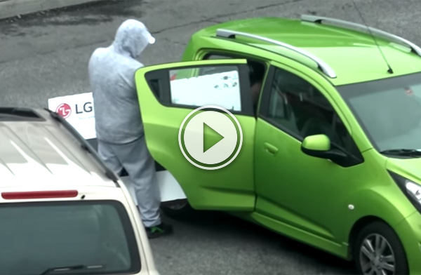 Man trying to cram an LG HDTV into his green Chevrolet car!