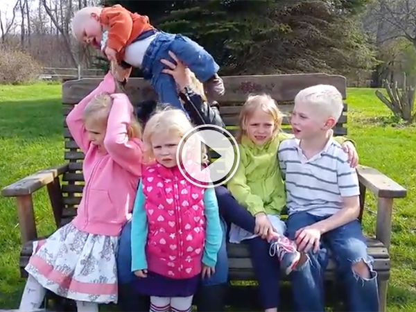 A family with five kids pose for a photo on a park bench!