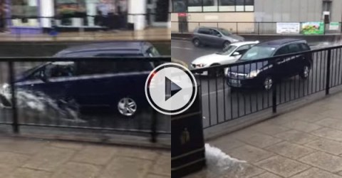 A black SUV running through a water-logged road and splashing water!