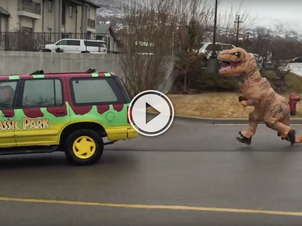 Dude in a T-Rex costume chases a Jurassic Park colored van!